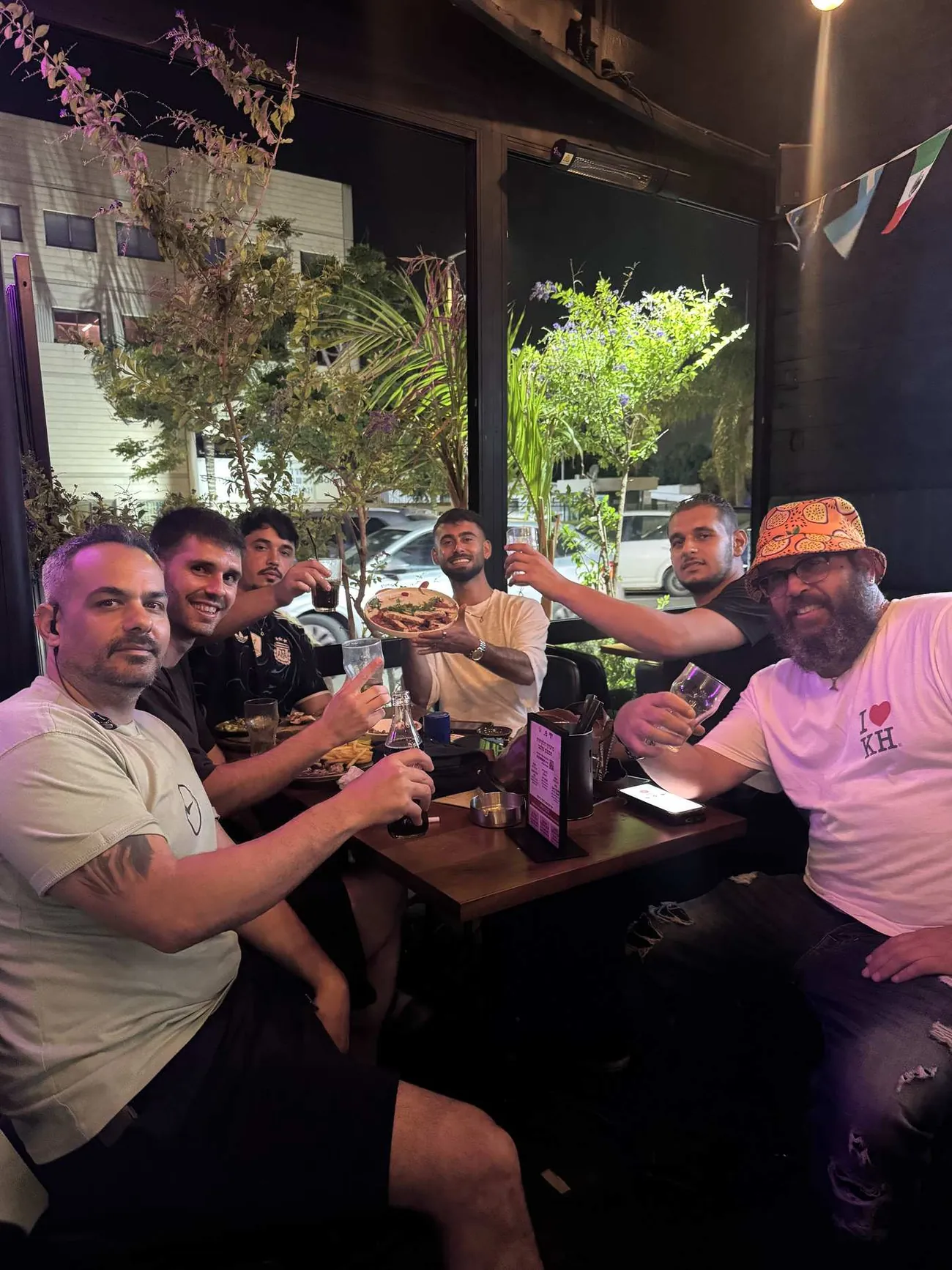 חבורה מרימה כוסית סביב שולחן בנישה בר